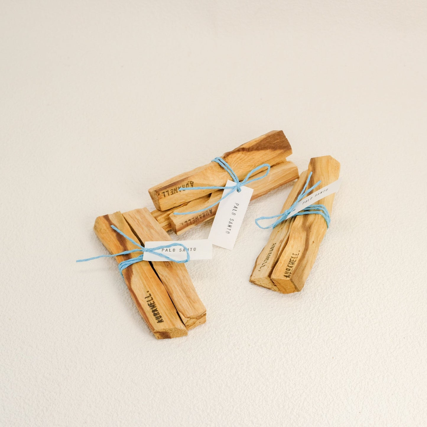 Three wooden incense sticks tied with blue string on a beige background